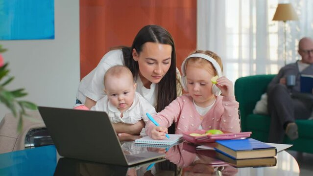 Young mother help preteen daughter doing homework on laptop