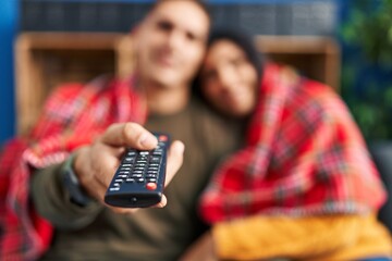 Man and woman couple hugging each other watching tv at home