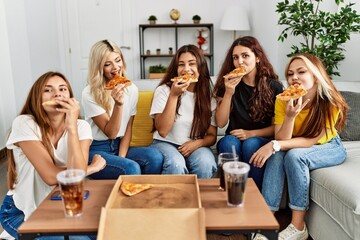 Group of young woman friends smiling happy eating pizza at home.