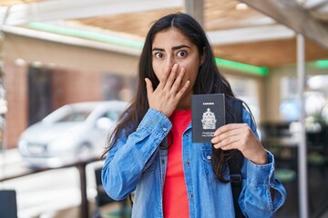 Young teenager girl holding canada passport covering mouth with hand, shocked and afraid for...