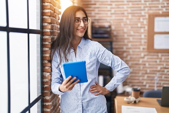 Young hispanic girl business worker smiling confident using touchpad at office