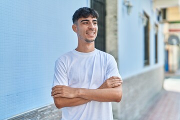 Obraz premium Young hispanic man standing with arms crossed gesture at street