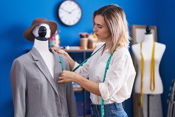 Young woman tailor measuring jacket at clothing factory