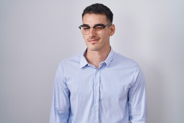 Handsome hispanic man wearing business clothes and glasses winking looking at the camera with sexy...