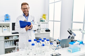Fototapeta premium Middle age hispanic man smiling confident wearing scientist uniform at laboratory