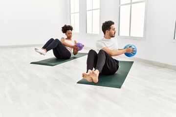 Obraz premium Young african american woman and hispanic man exercising at pilates room, stretching body and doing yoga pose, training strength and balance