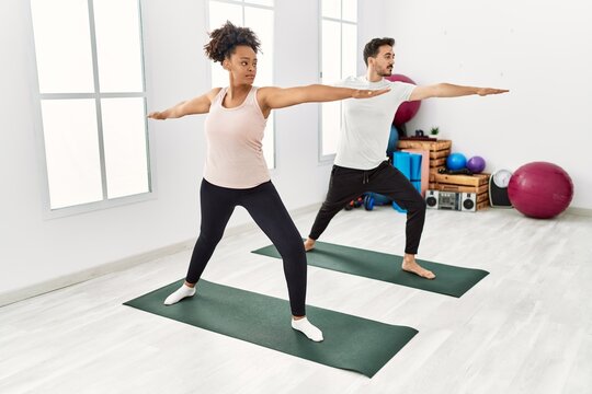 Young african american woman and hispanic man exercising at pilates room, stretching body and doing yoga pose, training strength and balance - Powered by Adobe