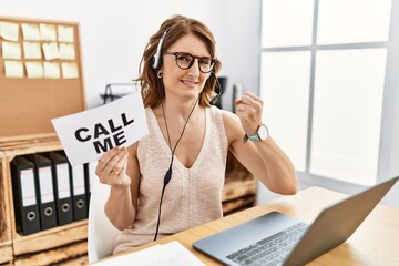 Middle age brunette woman wearing operator headset holding call me banner very happy and excited...