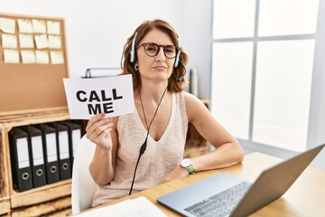 Middle age brunette woman wearing operator headset holding call me banner looking sleepy and tired,...