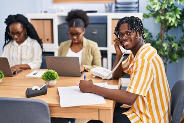 African american friends business workers sitting on table talking on the telephone working at office