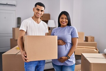 Young hispanic couple expecting a baby moving to a new home smiling with a happy and cool smile on face. showing teeth.