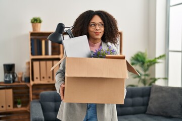 Young african american woman moving to a new office holding box with items smiling looking to the...