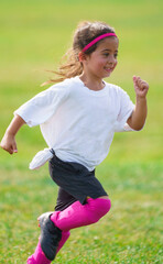 Excited young girl running on peewee soccer field learnings and playing football game with...