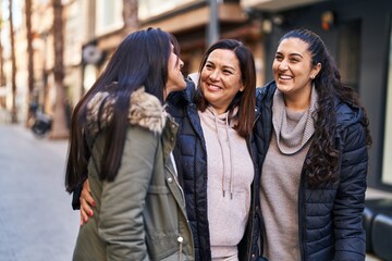 Three woman mother and daughters hugging each other at street