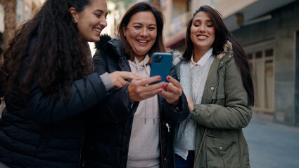 Mother and daugthers using smartphone standing together at street