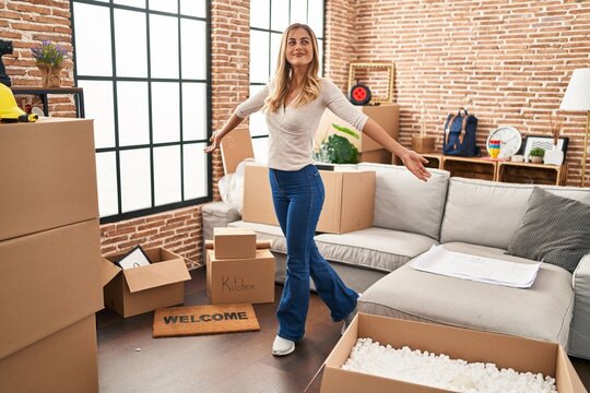 Young blonde woman smiling confident standing with open arms at new home