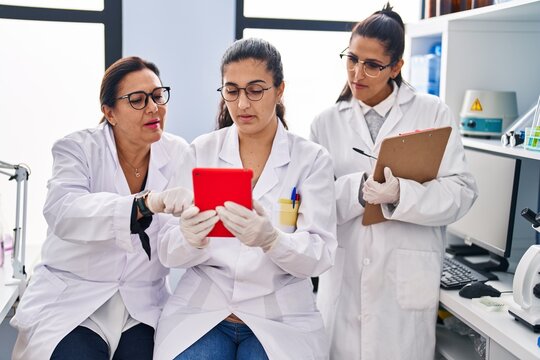 Three woman scientists using touchpad write on checklist at laboratory