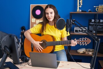Young woman musician singing song playing classical guitar at music studio