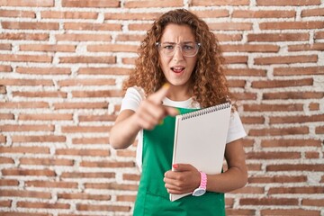 Young caucasian woman holding art notebook pointing displeased and frustrated to the camera, angry and furious with you