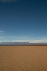 Fototapeta na wymiar View of the arid desert in Barreal Blanco, in San Juan, Argentina. The Andes mountains in the horizon under a deep blue sky.