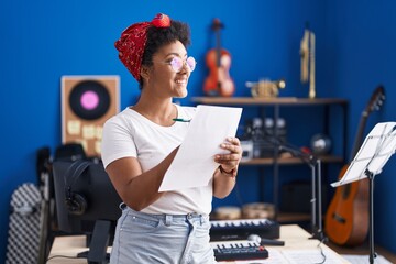 African american woman musician composing song writing on paper at music studio