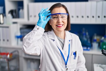 Middle age woman scientist smiling confident at laboratory