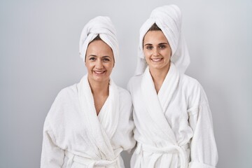 Middle age woman and daughter wearing white bathrobe and towel with a happy and cool smile on face. lucky person.