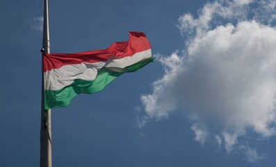National flag of Hungary against the clear blue sky. This is the flag in front of the building of the Hungarian Parliament.