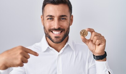 Handsome hispanic man holding litecoin cryptocurrency coin pointing finger to one self smiling happy and proud