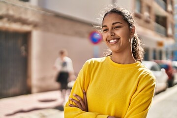 Naklejka premium Young african american woman smiling confident standing with arms crossed gesture at street