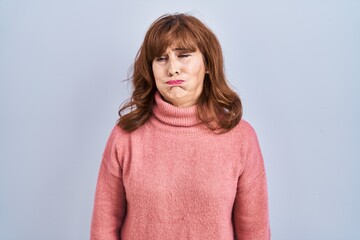 Middle age hispanic woman standing over isolated background puffing cheeks with funny face. mouth...