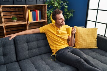 Young hispanic man listening to music drinking coffee at home