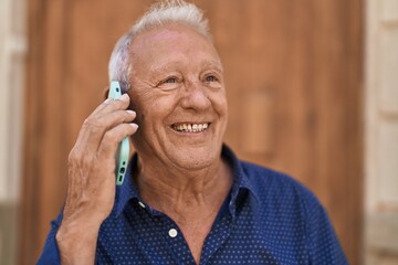Senior grey-haired man smiling confident talking on the smartphone at street