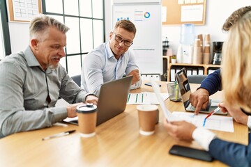 Group of middle age business workers working. Man smiling happy and looking to the camera at the office.