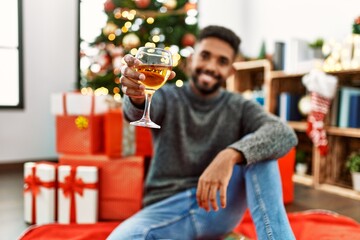 Young african american man smiling happy celebrating christmas drinking champagne at home.