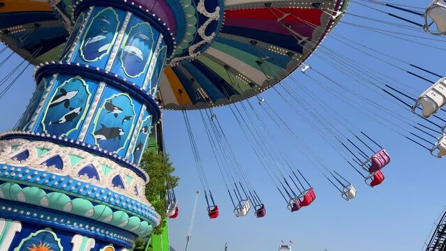 swing chain on which empty seats spin Preparing the park for work Checking the swing for serviceability Expectation of joy and happiness against the background of the sky All the colors of rainbow