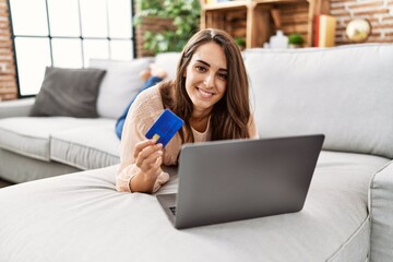 Young hispanic woman smiling confident using laptop and credit card at home