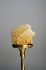Natural sweet useful product. Close-up of light transparent honeycombs on a golden stand on a white background. Natural honey and wax