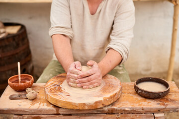 Potter with wet clay pot in hands. pottery crafter man hands sculpt in clay