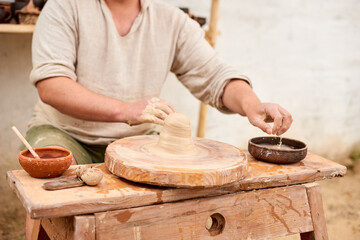 male master in a light linen shirt shows how to sculpt from clay in master class