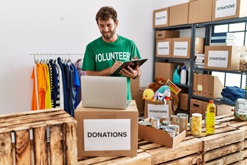 Young hispanic volunteer man smiling happy working at charity center.