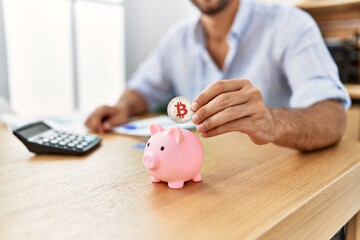 Obraz na płótnie Canvas Businessman insert bitcoin in piggy bank at the office.