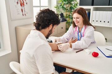 Fototapeta premium Man and woman wearing doctor uniform having blood analysis at clinic