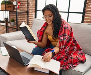 Young chinese woman studying sitting on sofa at home