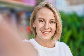 Young blonde woman smiling confident make selfie by camera at street