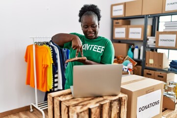 Young african american woman wearing volunteer uniform speaking using deaf sign language at charity center