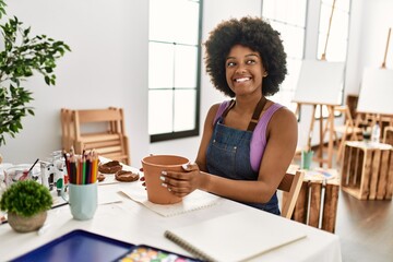 Young african american woman smiling confident making clay pot at art studio