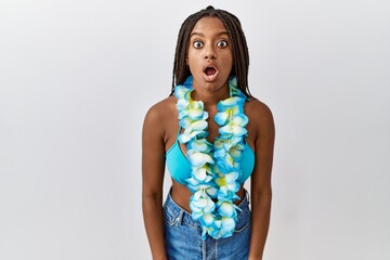 Young african american woman with braids wearing bikini and hawaiian lei afraid and shocked with...