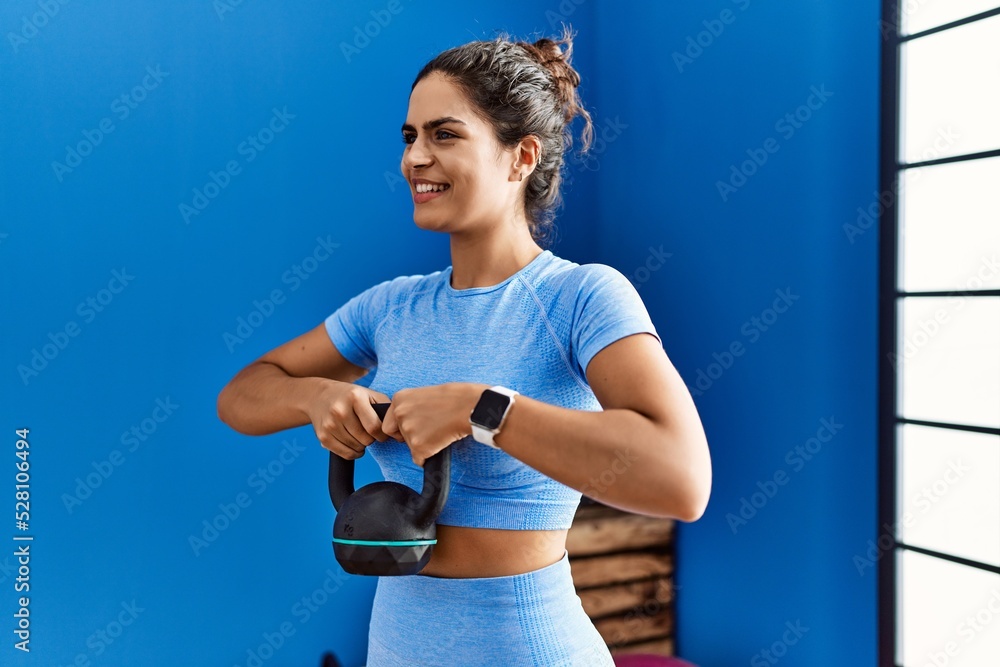 Canvas Prints young latin woman wearing sportswear training using kettlebell at sport center