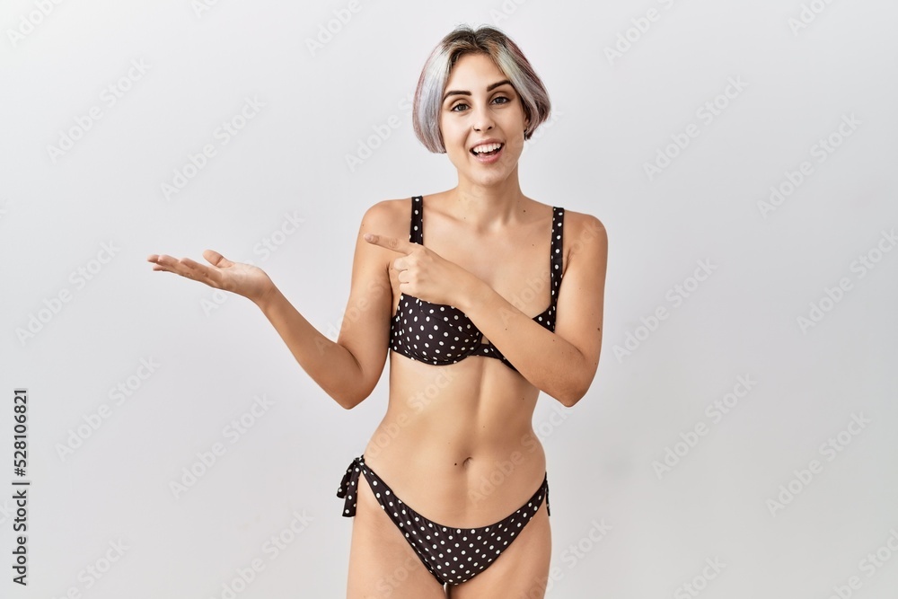 Sticker young beautiful woman wearing swimsuit over isolated background amazed and smiling to the camera whi